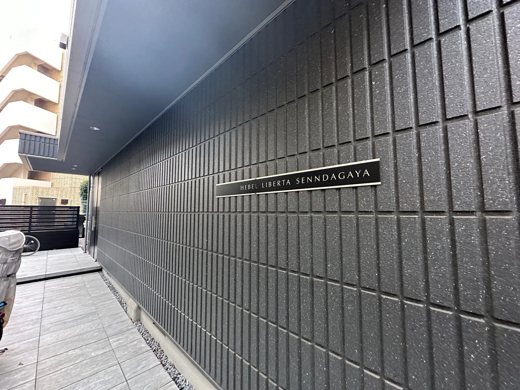 グレーのタイル壁とホテルリベルタ千駄ヶ谷の看板があるモダンな外観の通路