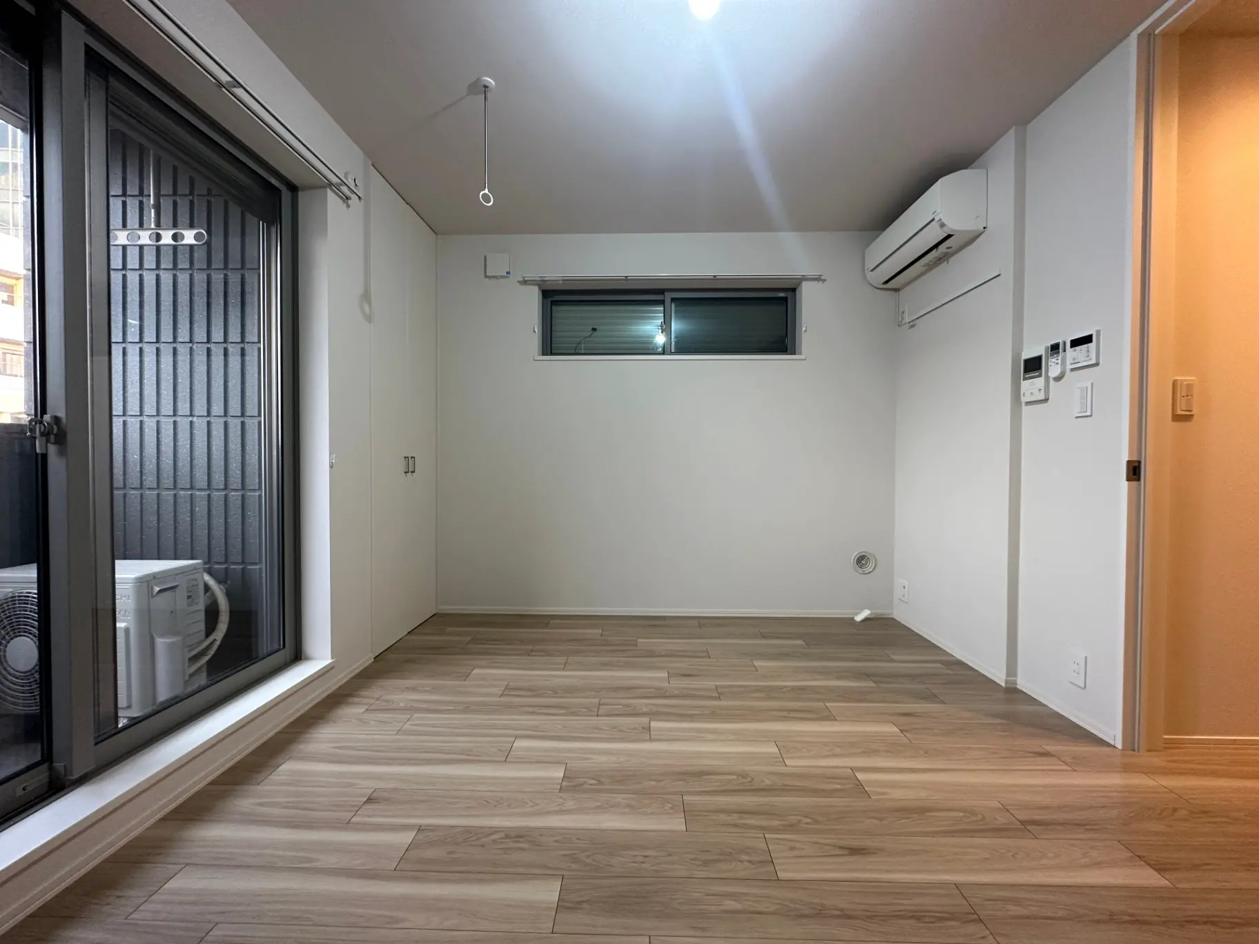 空の部屋と窓、木製フローリングが特徴のシンプルなインテリアデザイン