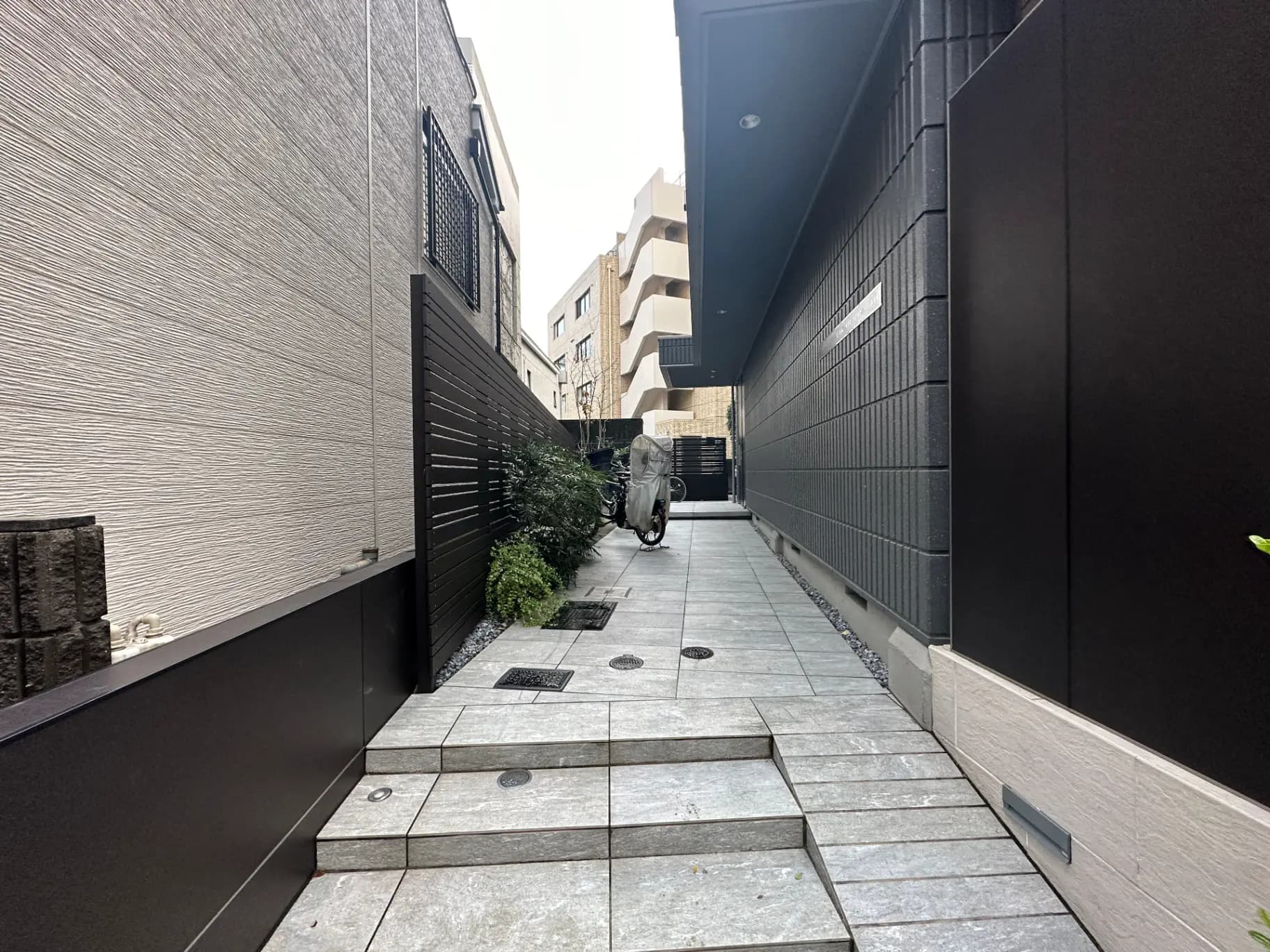 都市の閑静な住宅街の石畳の通路、現代的な建物の壁と植物装飾