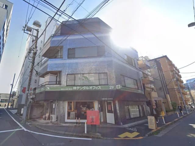 都市の角にある現代的な建物、1階のカフェと2階のビジネス看板、晴れた日の青空