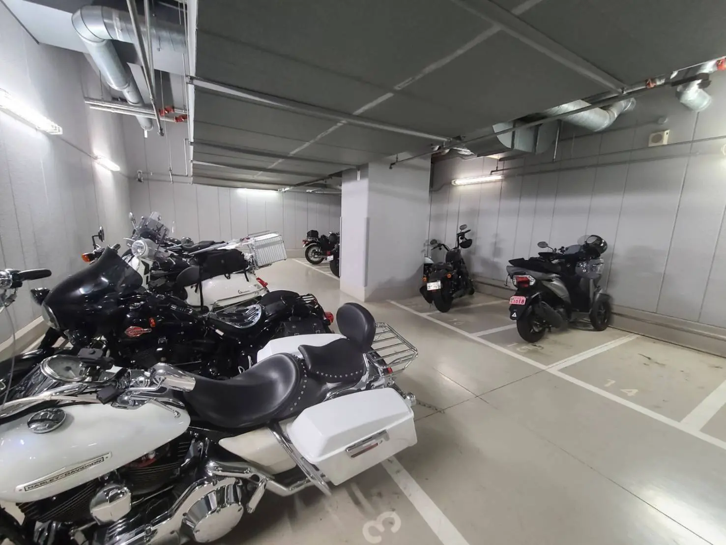 地下駐輪場で整理されたバイクとスクーター、清潔で明るい照明のある安全な駐車スペース