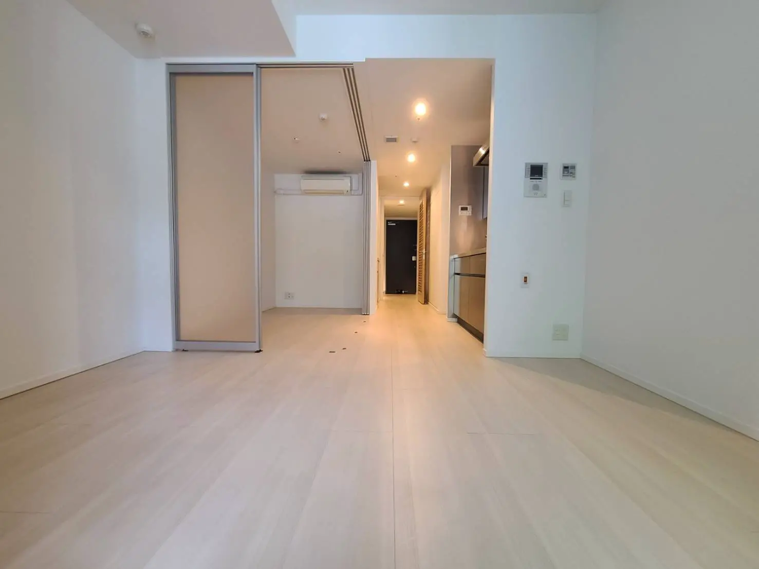 明るい室内と木製フローリングのある新築マンションの玄関ホール