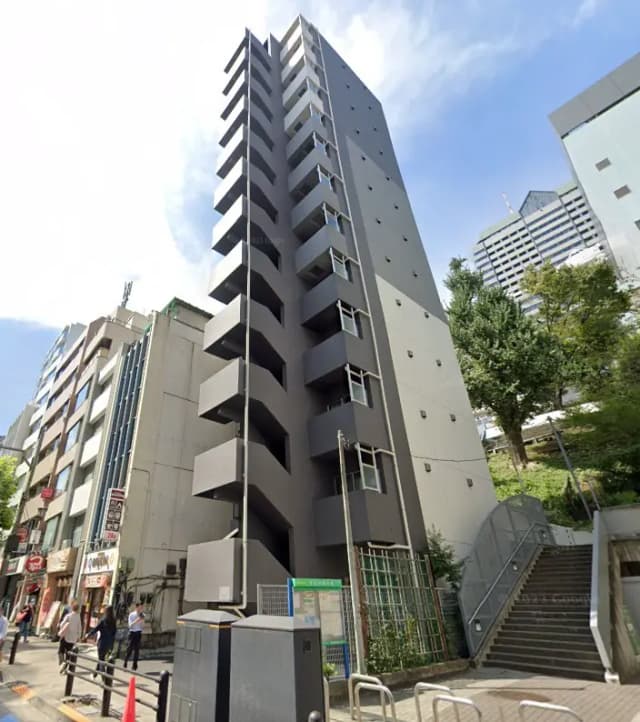 - 現代的なデザインの高層ビル、隣接する商業施設と緑の木々が見える都市景観