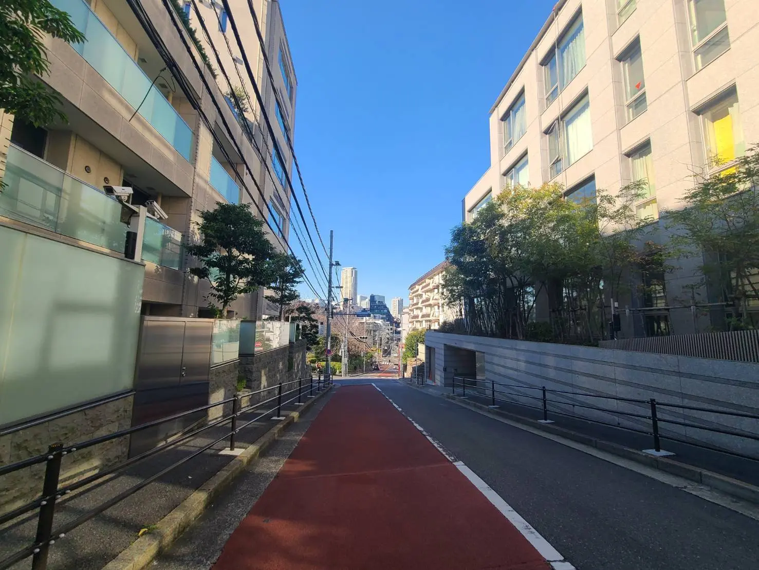 青空の下、現代的な都市の風景、歩道と赤い自転車レーンが特徴的な街路