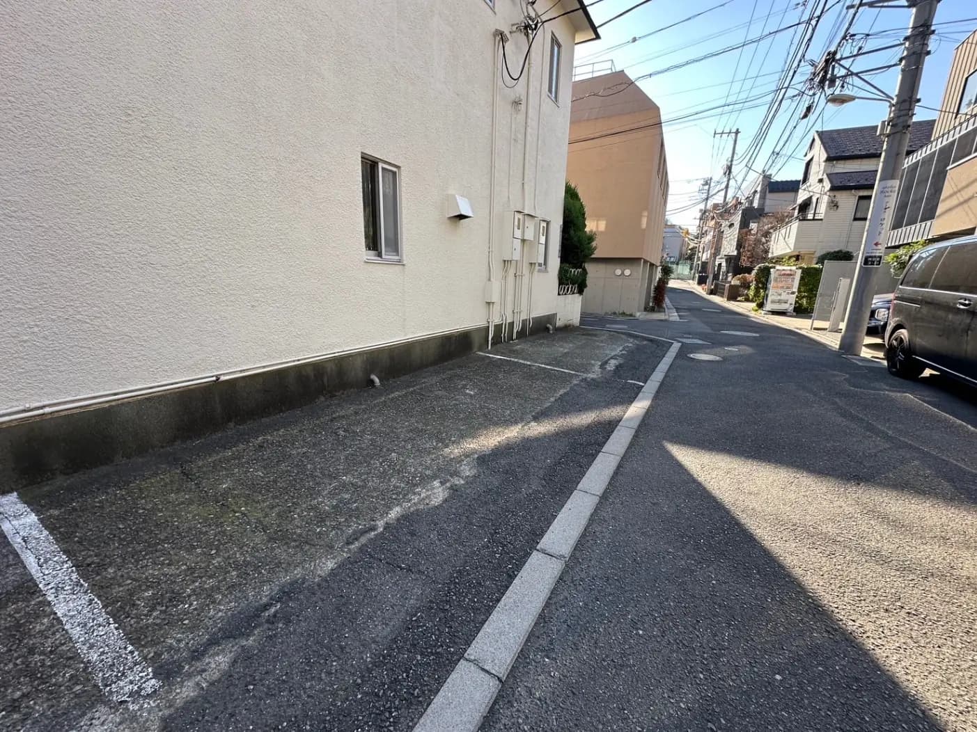 日本の住宅街のアスファルト道路、晴れた日の影と駐車された車