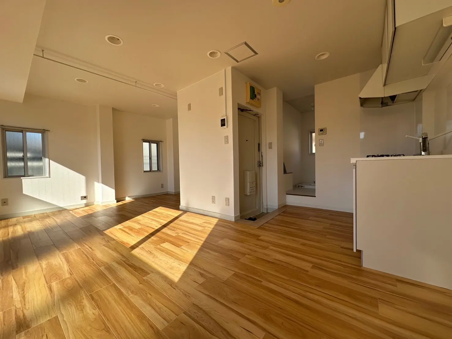 明るい自然光が差し込む広々とした空間、木製フローリングの新築マンションのリビングルーム