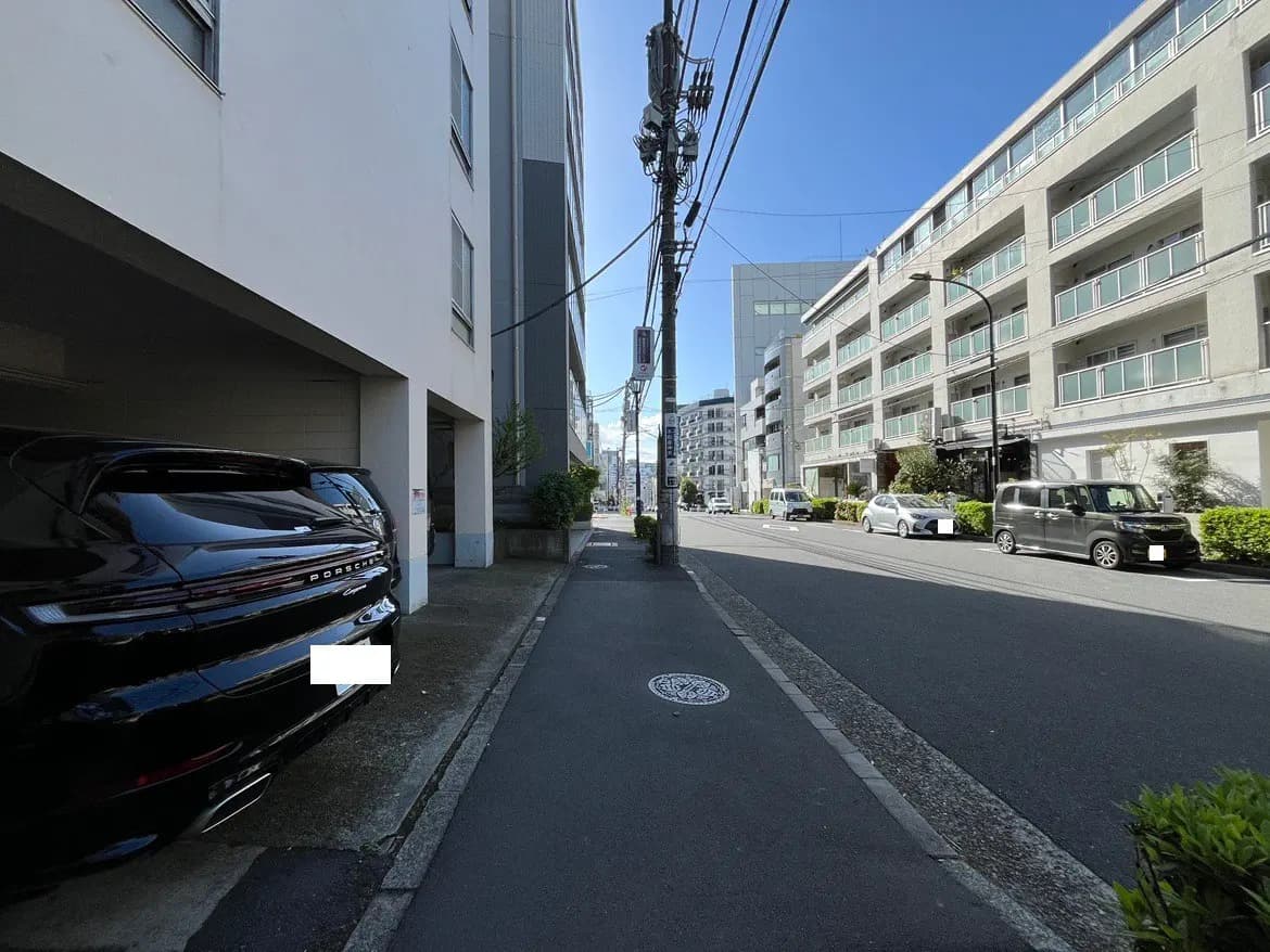 - ポルシェの車と周囲のビルが並ぶ都市の風景、青空と清々しい街並みが広がる通りの様子