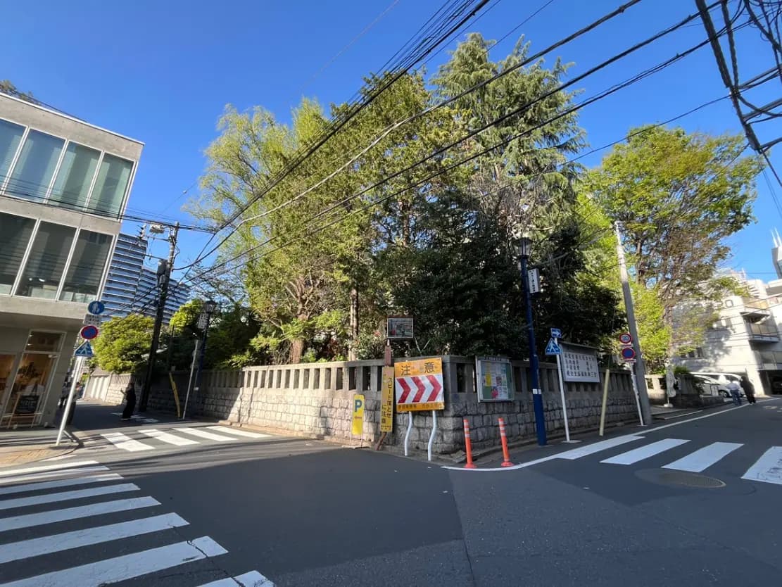 - 道路交差点と石垣に囲まれた緑豊かなエリア、青空と電線が見える街並み