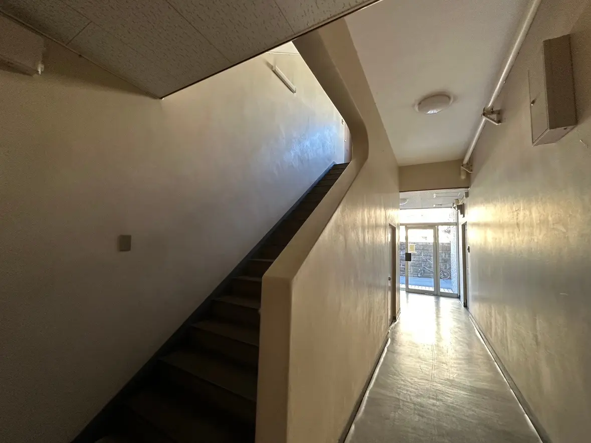 狭い室内の階段と廊下、自然光が差し込む出口のドア