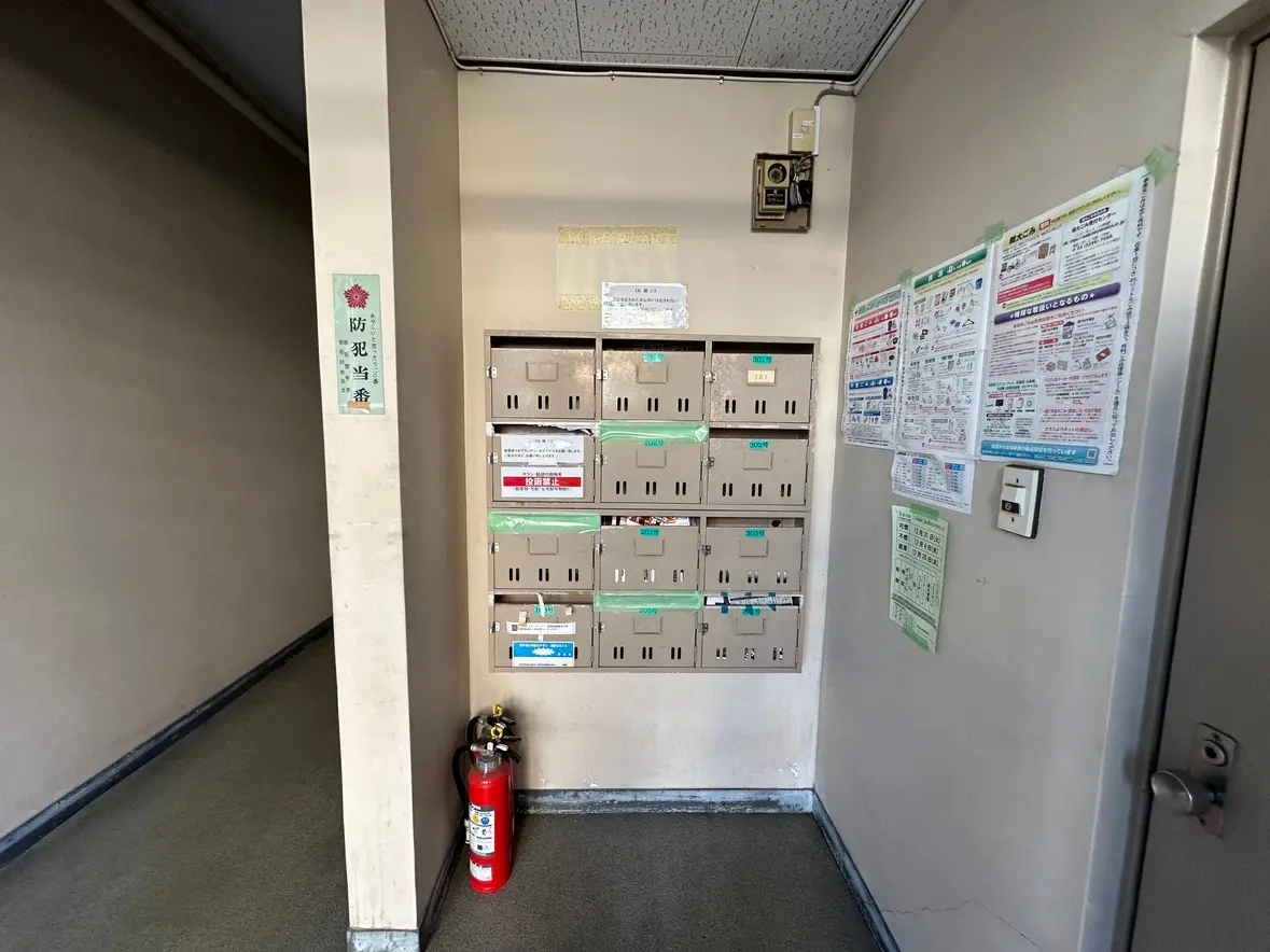 日本のアパートのエントランスホール、郵便受け、防災用具と掲示物がある内部の様子