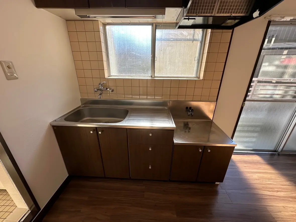 日当たりの良いキッチン、木目調キャビネット、ステンレスシンク、タイルの壁