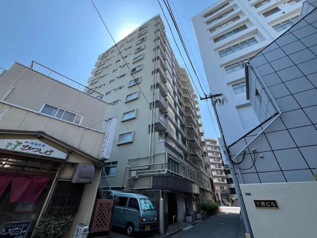 - 地元の飲食店の看板が見える道沿いの風景、高層マンションと住宅が並ぶ都市の景観