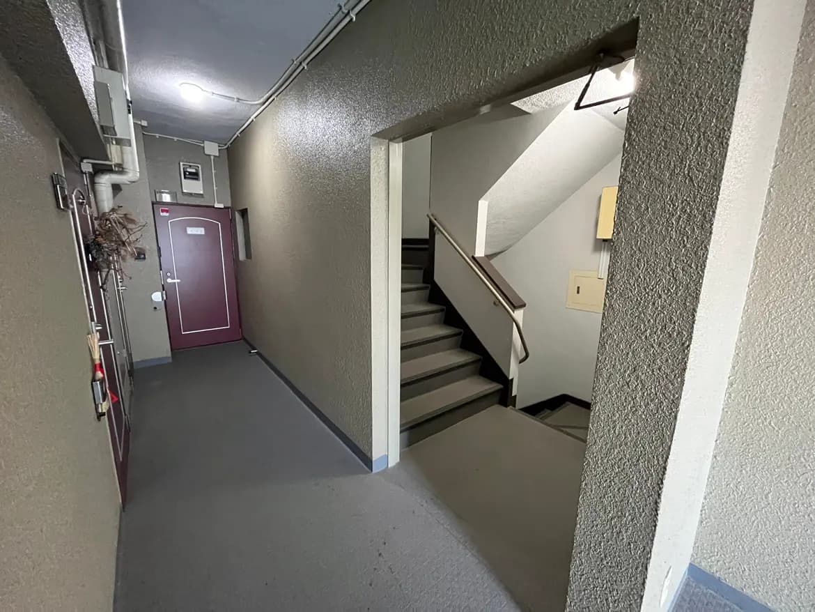 - シンプルで清潔感のあるマンションの廊下、階段へのアクセスとドアが見える静かな空間