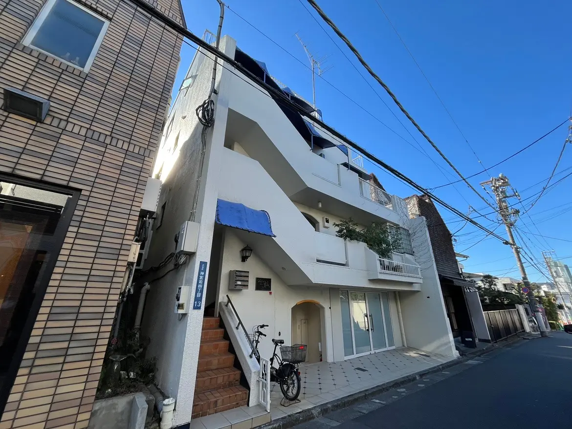 現代的なデザインの都市型マンション、晴れた日に撮影された青空の下、外観と自転車が置かれた歩道