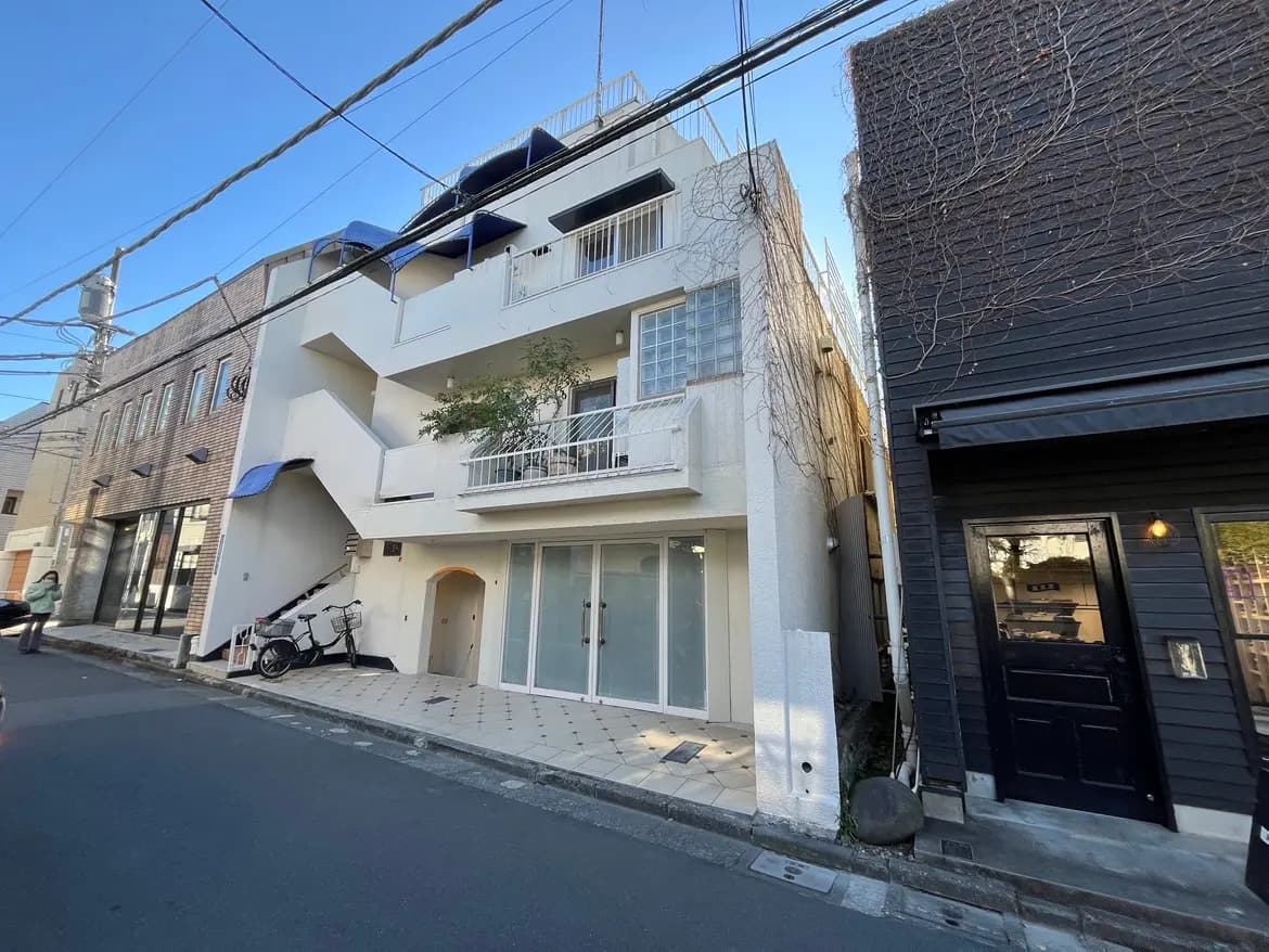 都市部に位置するモダンなデザインのアパート建物、晴れた日の外観、隣には黒い外壁の店舗