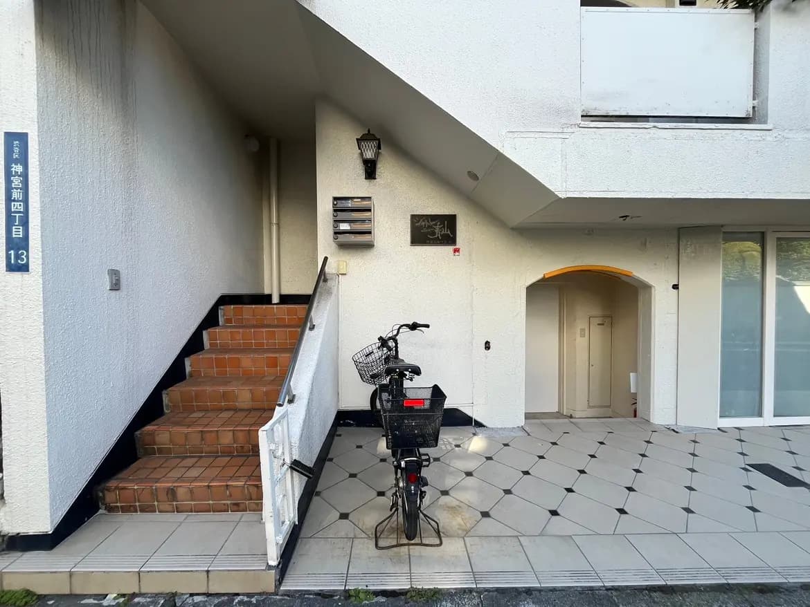 建物の入り口と階段、自転車が停まっている外観