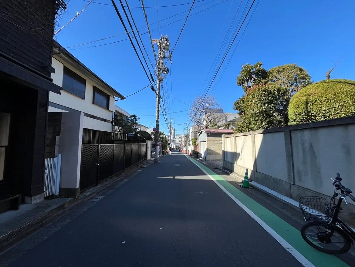 晴れた日の日本の住宅街、青空と整備された歩道、電信柱と自転車が見える静かな道路