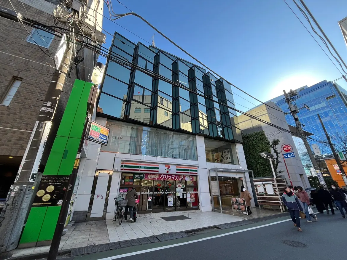 都市の通りにある現代的なビルとコンビニエンスストア、歩行者、晴れた日の都会の風景