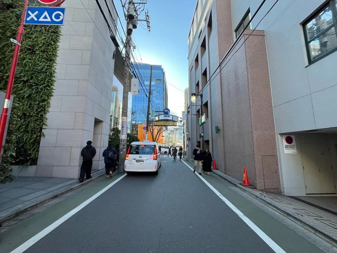 晴れた日の都市風景、ビルと青空、歩行者と走行中の白い車