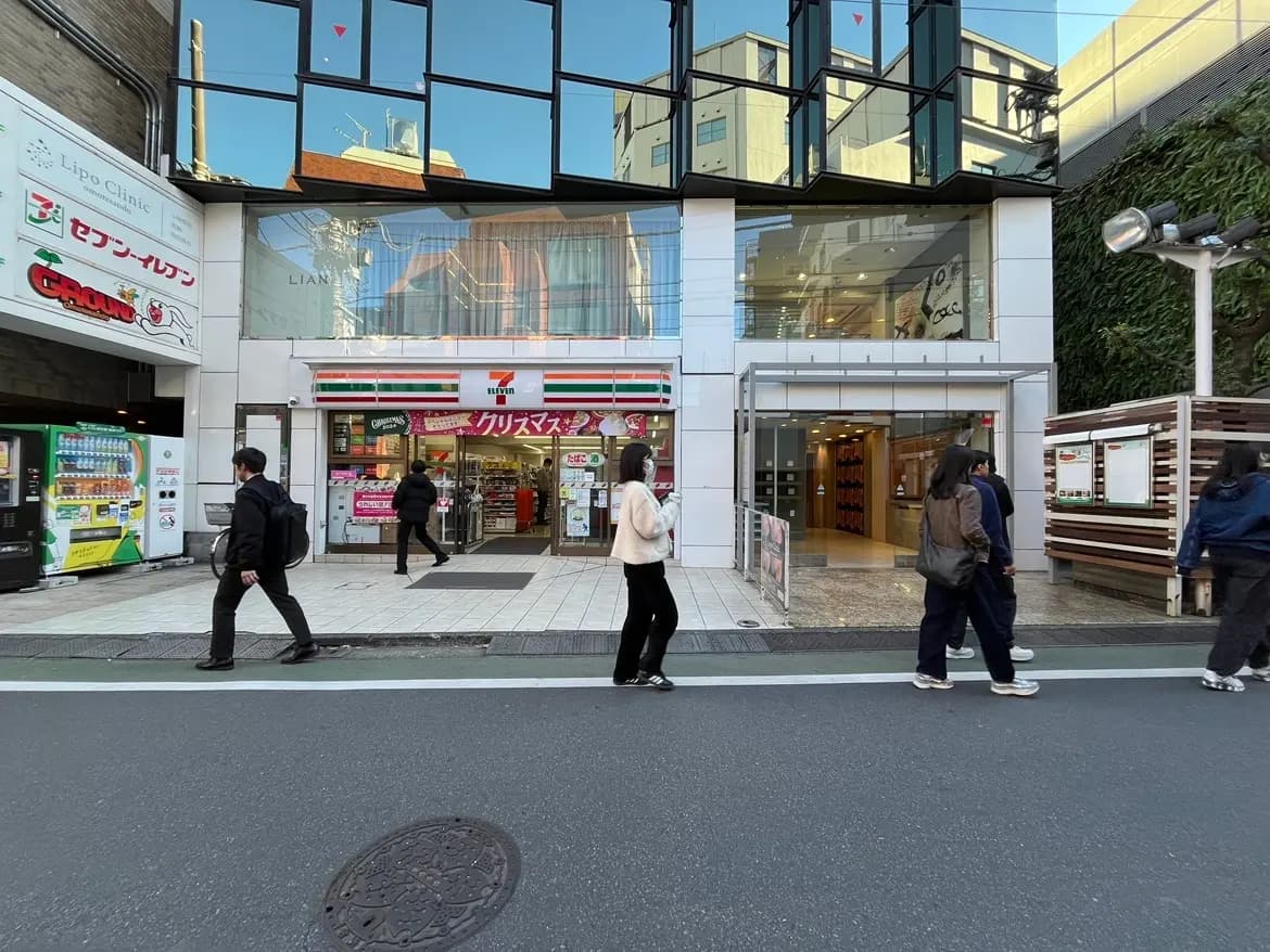 都市のコンビニエンスストアの外観、歩道を歩く人々と近代的な建築デザイン