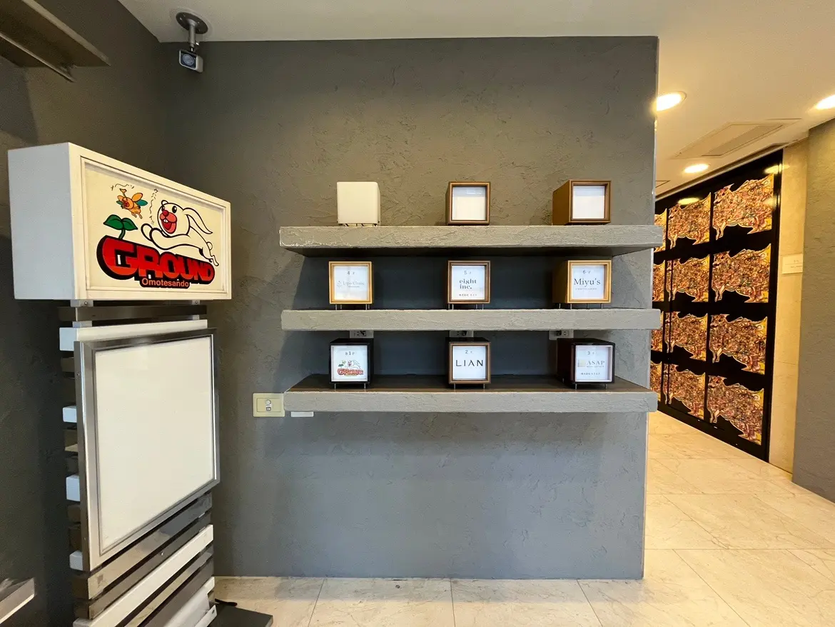 現代的な内装の店舗入口、壁に取り付けられた棚に商品やディスプレイボックスが展示されているインテリア