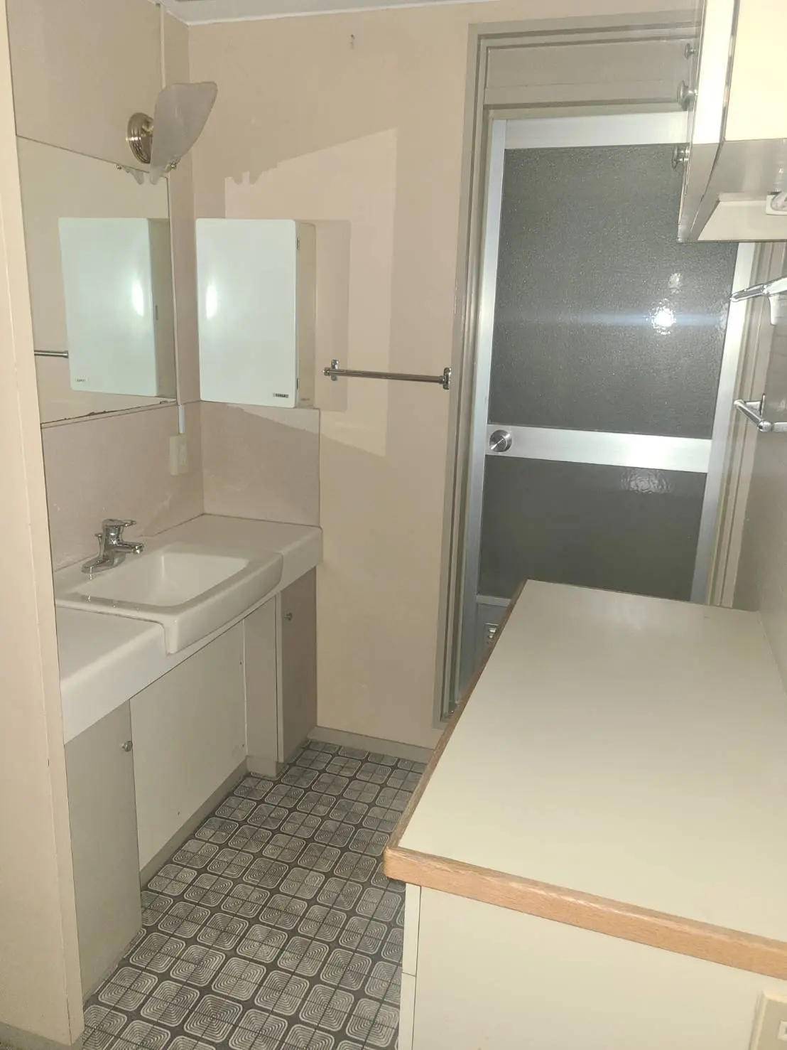 コンパクトな洗面所、白い洗面台と鏡、黒白タイルの床