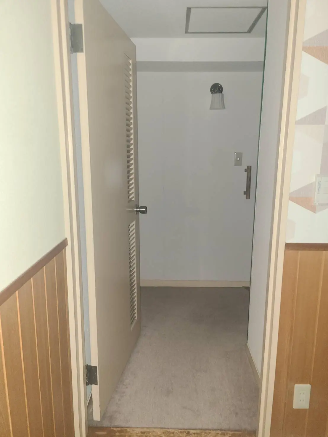 シンプルなデザインの室内の廊下、木製の手すりとカーペット、白い壁と天井のライト