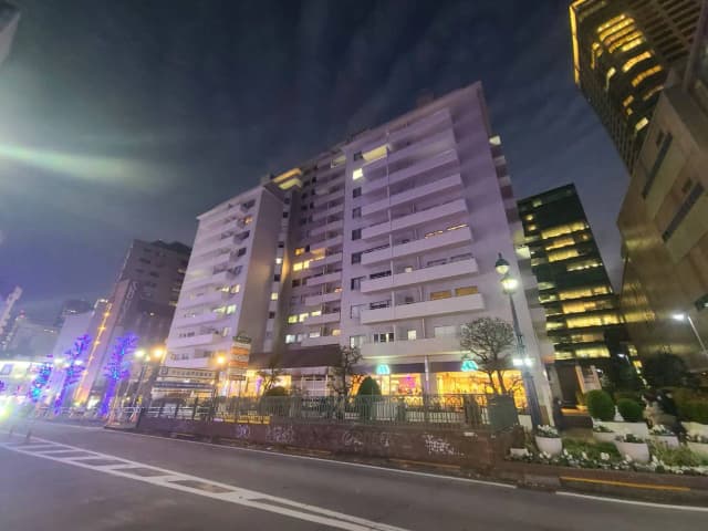 夜景の都市のアパートビル、通りのライトアップと建物の窓の灯り