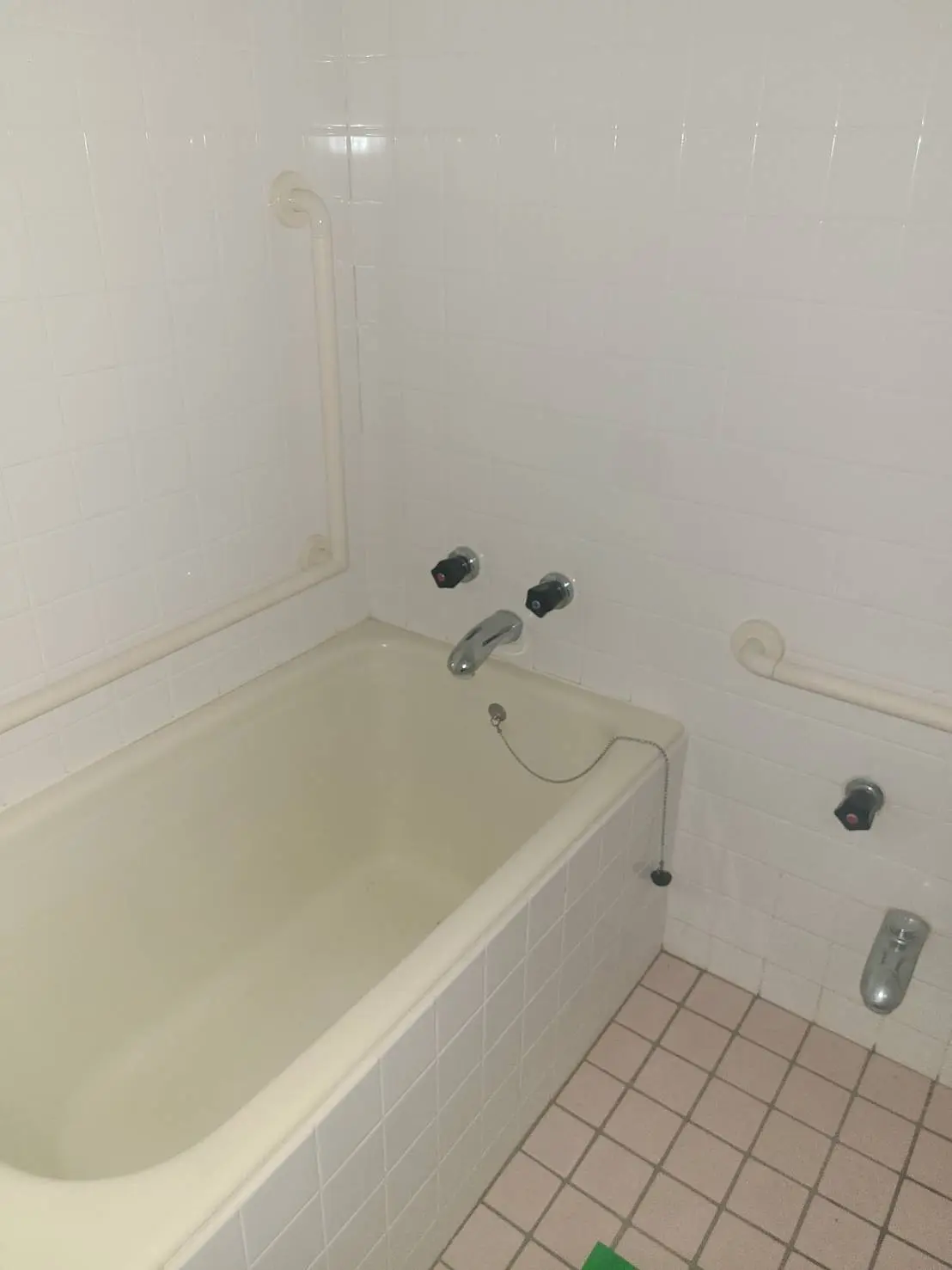 シンプルなデザインのバスルーム、白いタイル壁、バスタブ、手すり付き、クリーンなインテリア