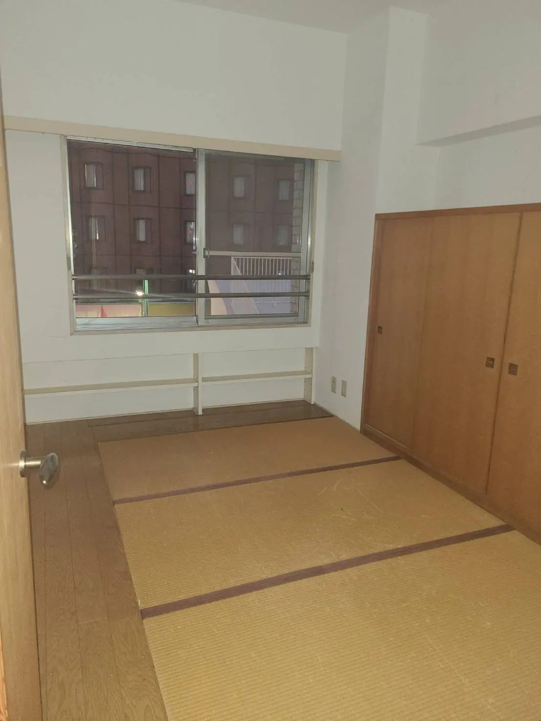 シンプルな和室、畳の床と木製の戸棚、大きな窓からの自然の光