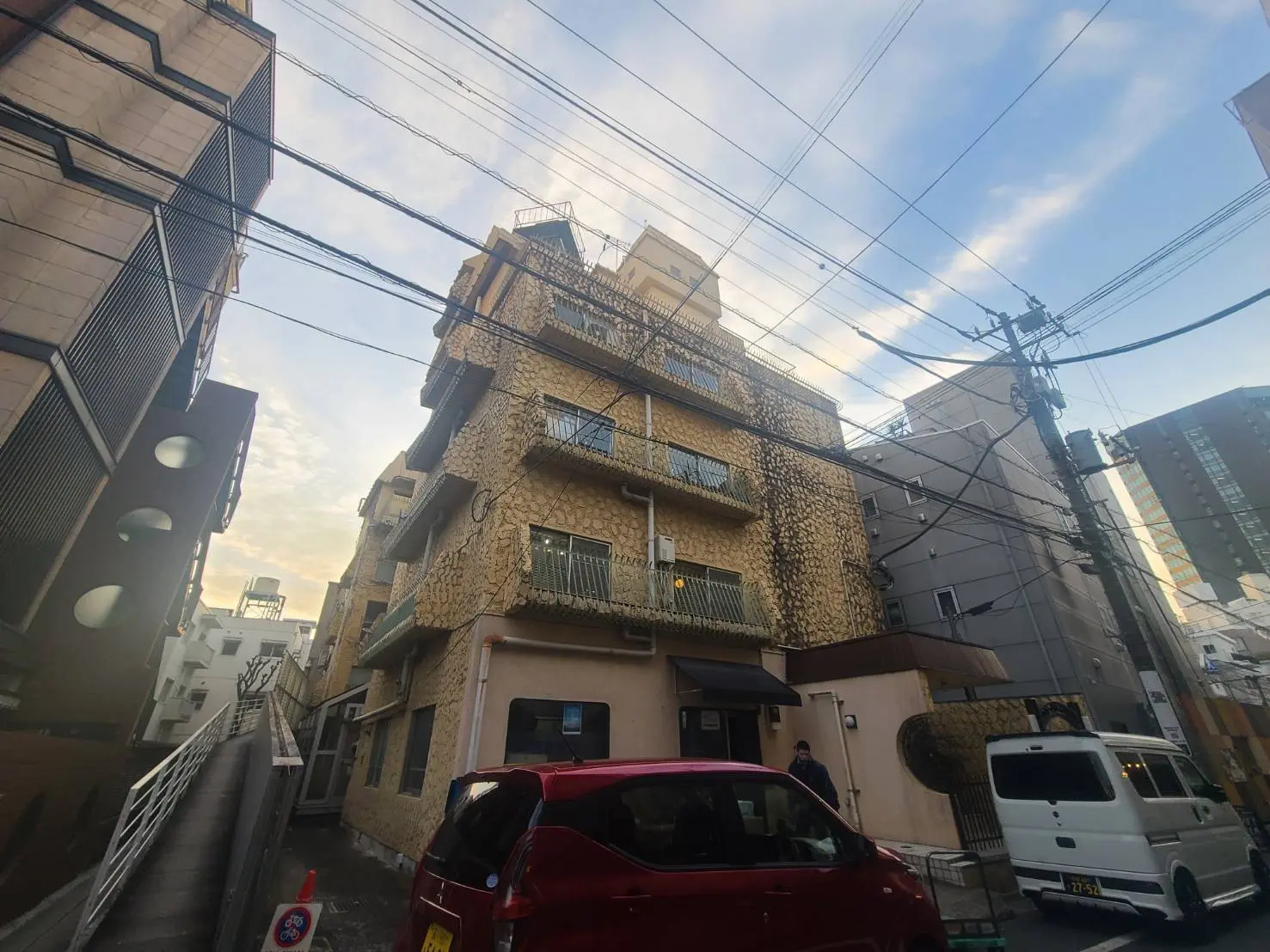 市街地にある独特な外壁のマンション、青空と電柱が見える都市の景観
