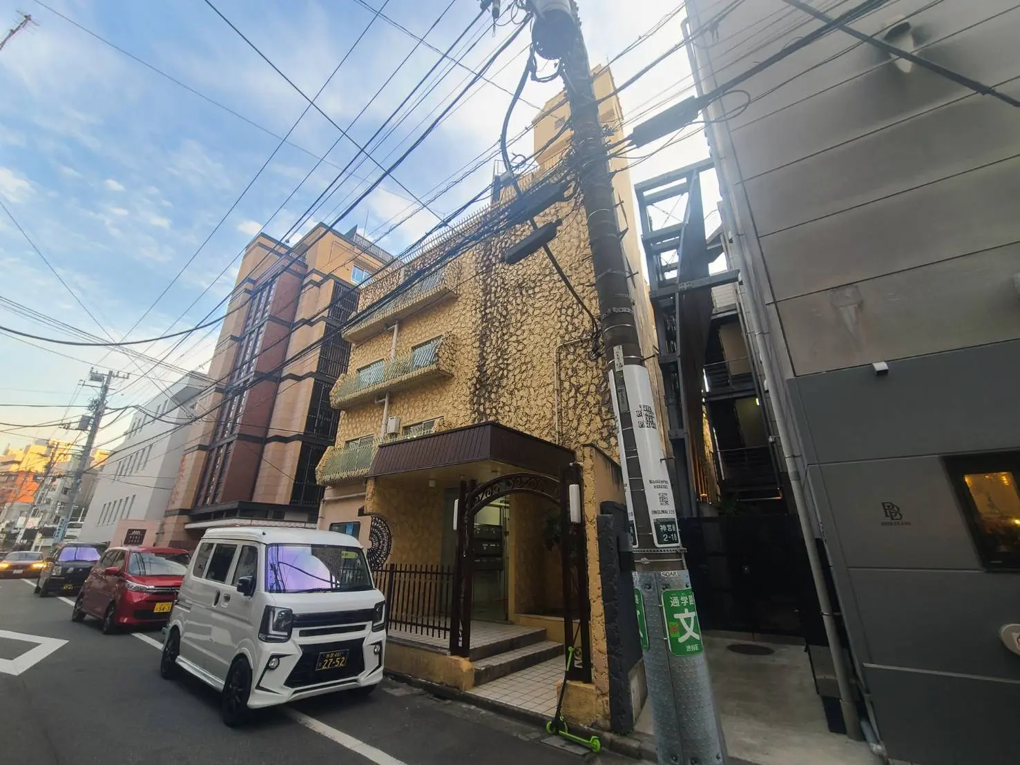 都市の住宅街に並ぶ様々なデザインの建物、晴れた日の街並みと駐車している車