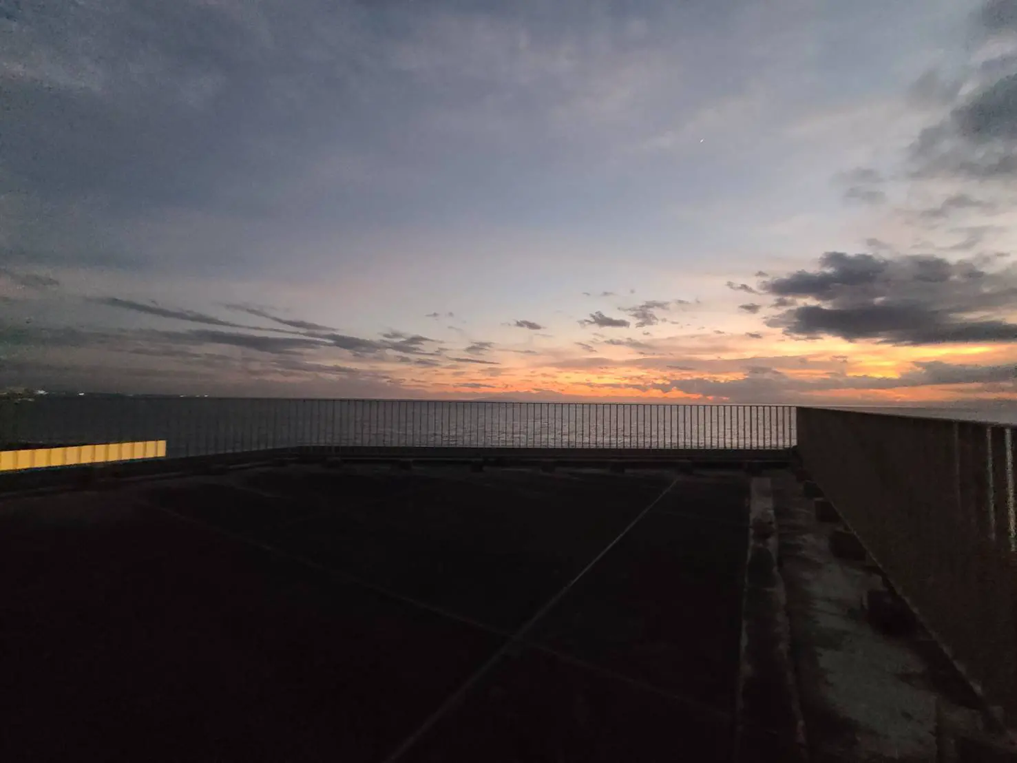 夕暮れ時の海辺の空と雲、手前には駐車場が見える落ち着いた景色
