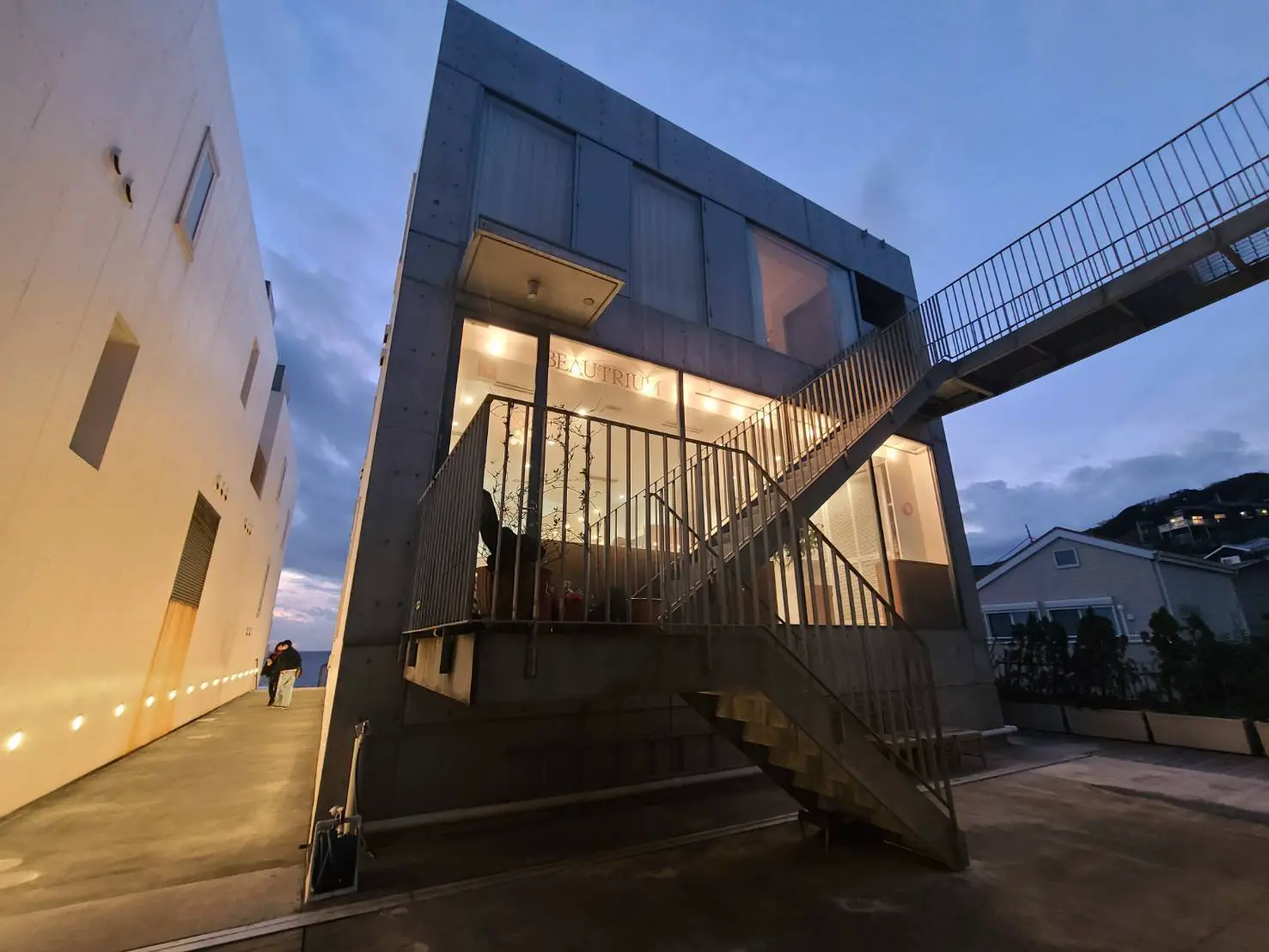 夕暮れ時のモダンな建築スタイルのビル、外灯と天候に照らされた階段と入口