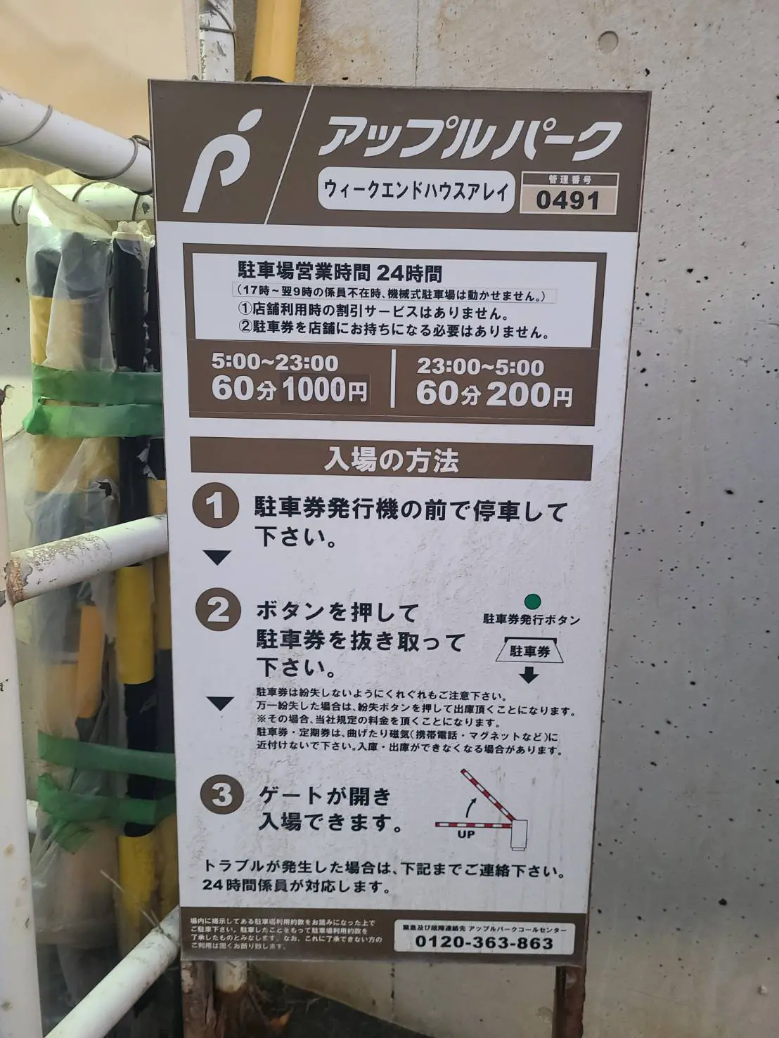 駐輪場の料金と規則を説明する看板、24時間営業のバイク用パーキングサービス案内