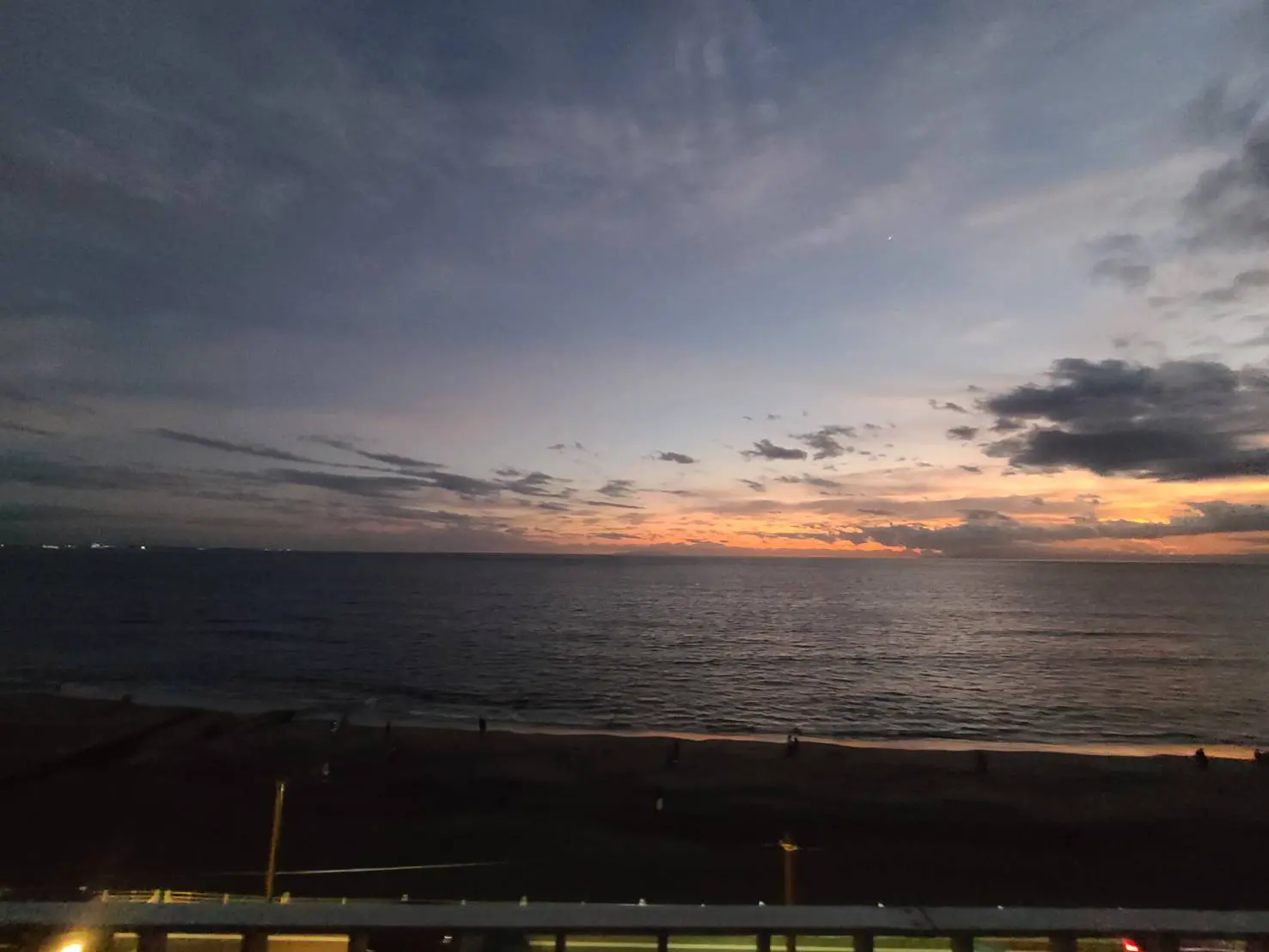 夕暮れ時の海岸線、穏やかな海とオレンジ色に染まる空、ビーチへ続く遊歩道