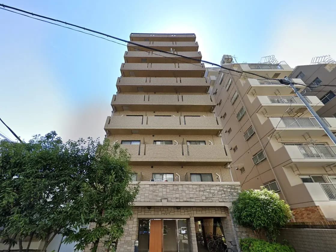 都市型マンションの外観、多階層建築で石造りのエントランス、自転車置き場が見える