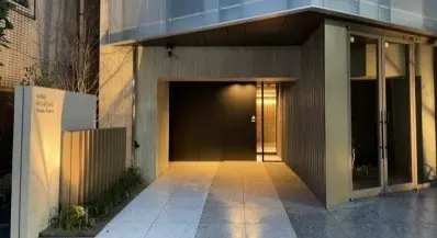 モダンな建築スタイルのマンションエントランス、照明が施されたアプローチウェイ、屋外植栽付き