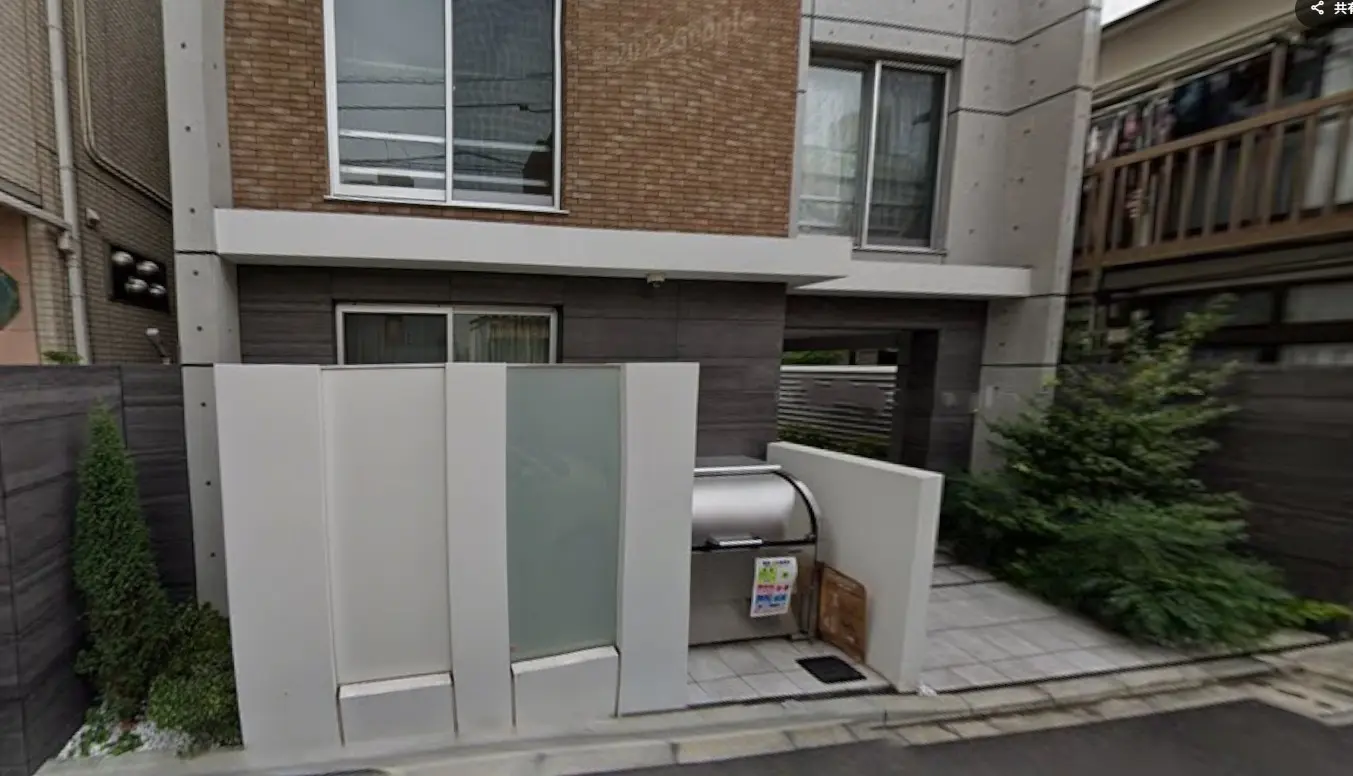 都市型モダン住宅の外観、ブラウンのレンガとダークウッドのデザイン、プライバシーを考慮した白いフェンス