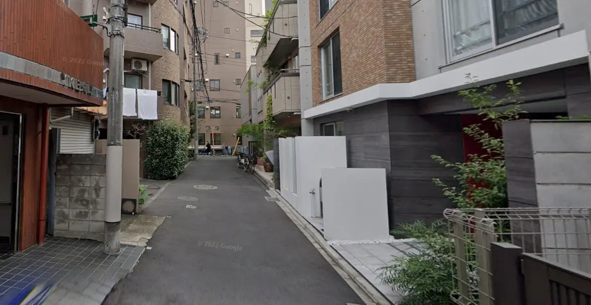 静かな住宅街の狭い路地、複数の自転車と洗濯物が干してある風景