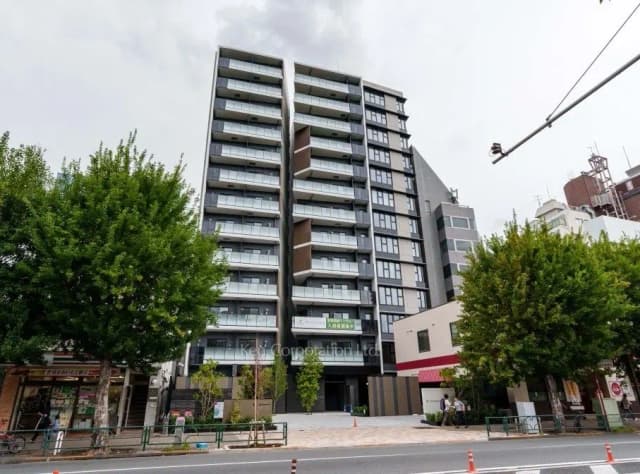 現代的な外観の都市型マンションビル、一階には小さな店舗も入居、緑豊かな木々と都市の風景