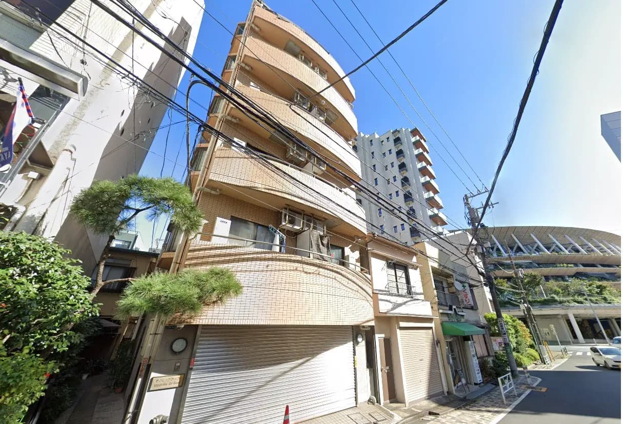 日差しが差し込む晴れた日の都市風景、タイル貼りの外壁を持つ茶色のアパート、裏通りに面していて電線が走る