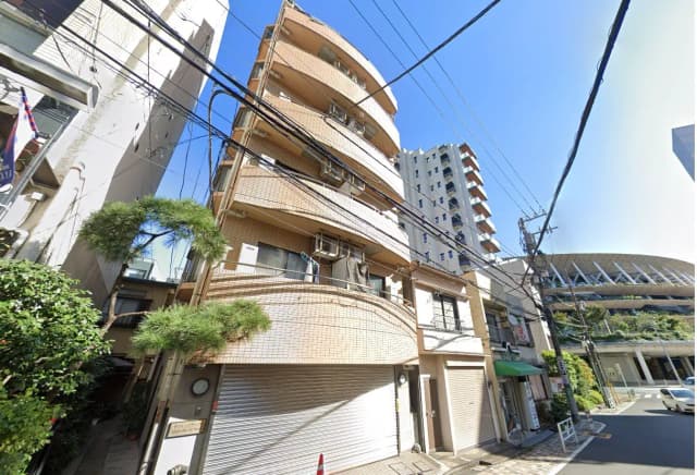 日差しが差し込む晴れた日の都市風景、タイル貼りの外壁を持つ茶色のアパート、裏通りに面していて電線が走る