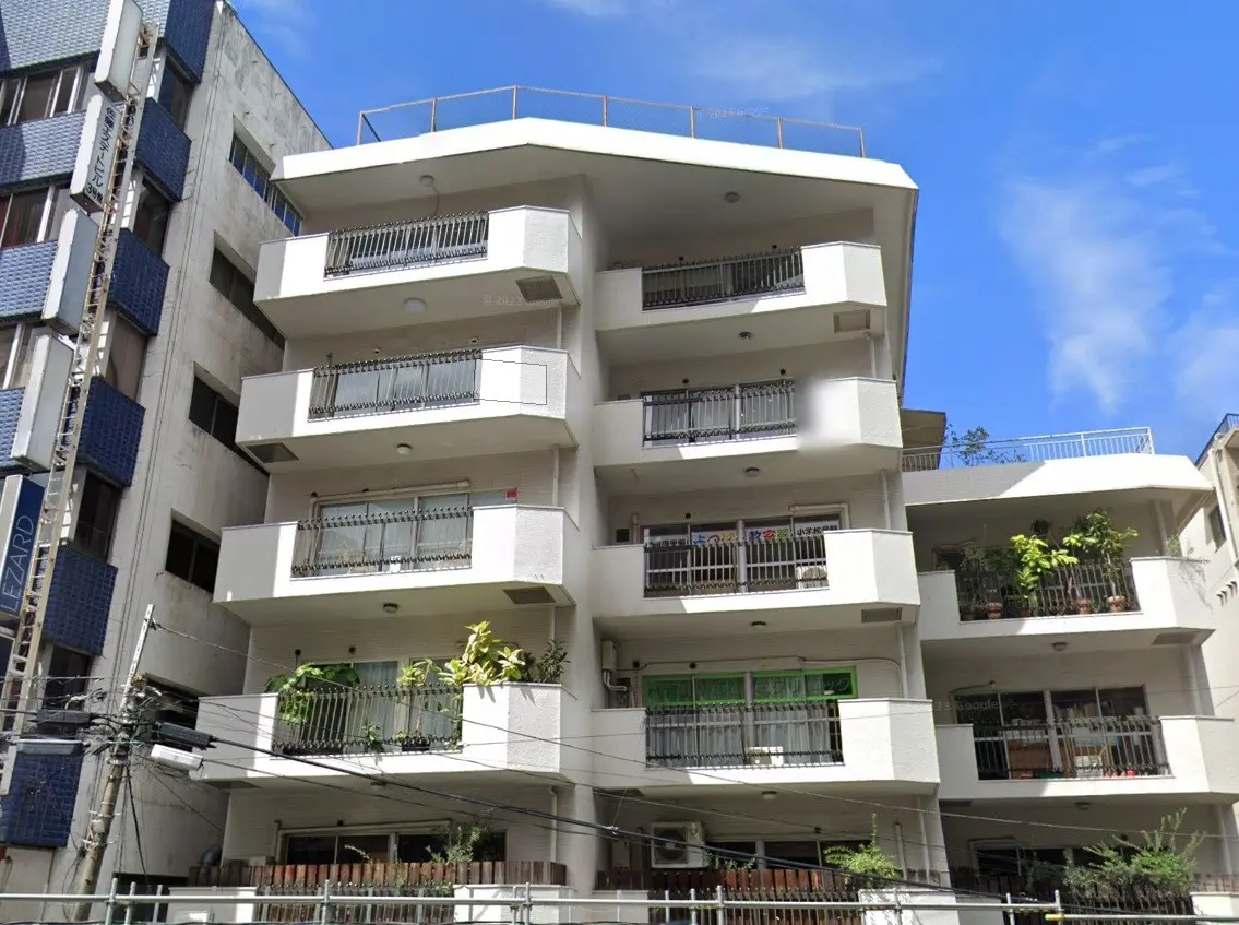 都市のマンション、白い外壁にバルコニー付きのアパート、晴れた日の青空