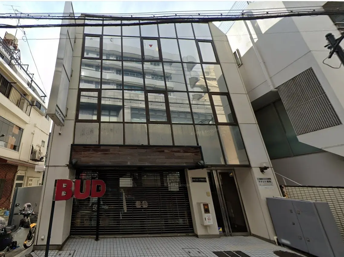 現代的な外観のビルとシャッター付きの店舗入り口、都会の風景と路上駐車のバイク