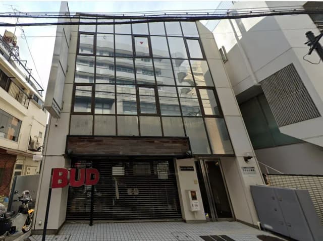 現代的な外観のビルとシャッター付きの店舗入り口、都会の風景と路上駐車のバイク