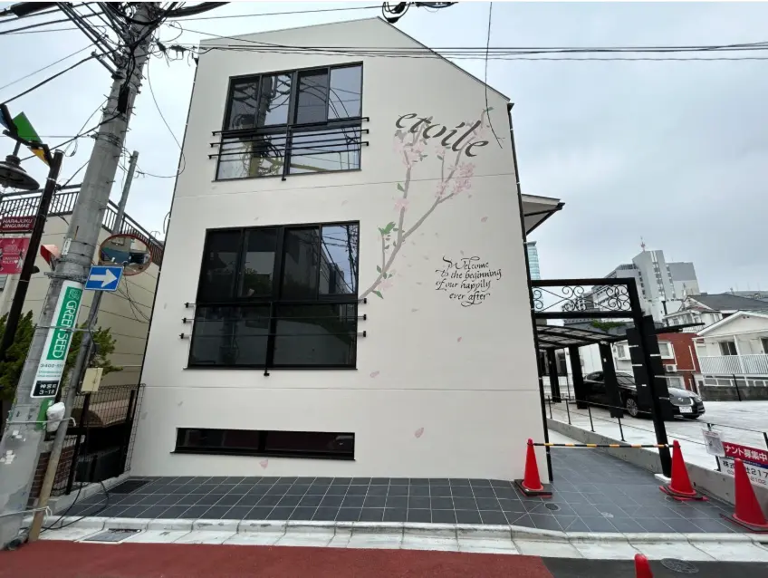 桜の壁画が描かれたモダンなビルの外観、都市風景と駐車場、天気が曇り空