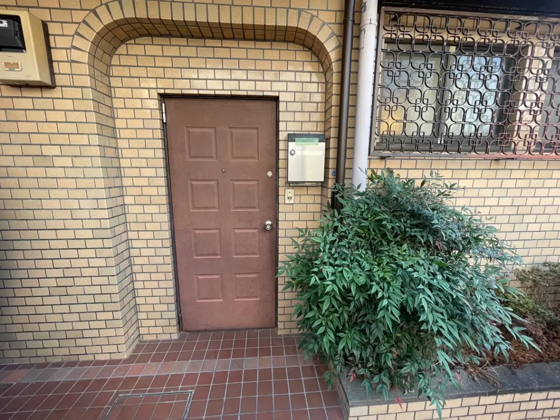 茶色の扉とモザイクガラスの窓が特徴的な都市型アパートメントの入口