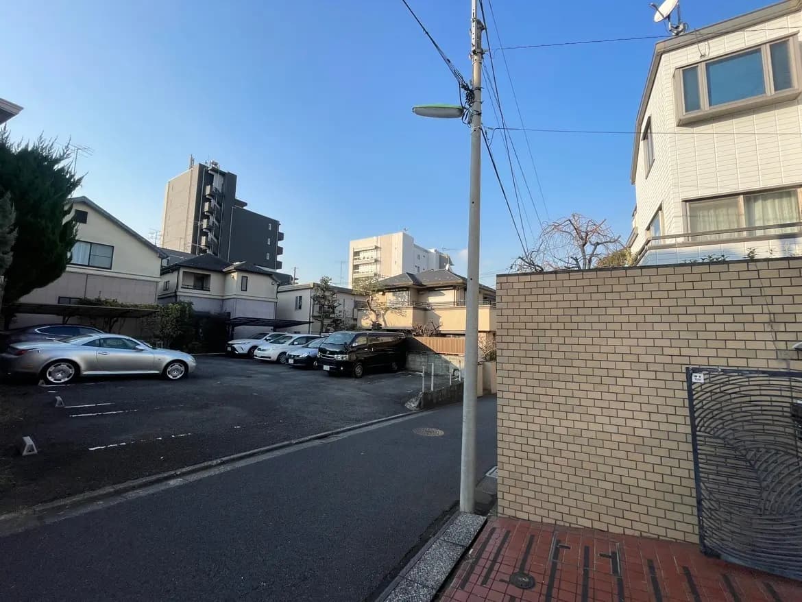 静かな住宅街の風景、壁に囲まれた駐車スペース、電柱と建物、晴れた日の早朝または夕方
