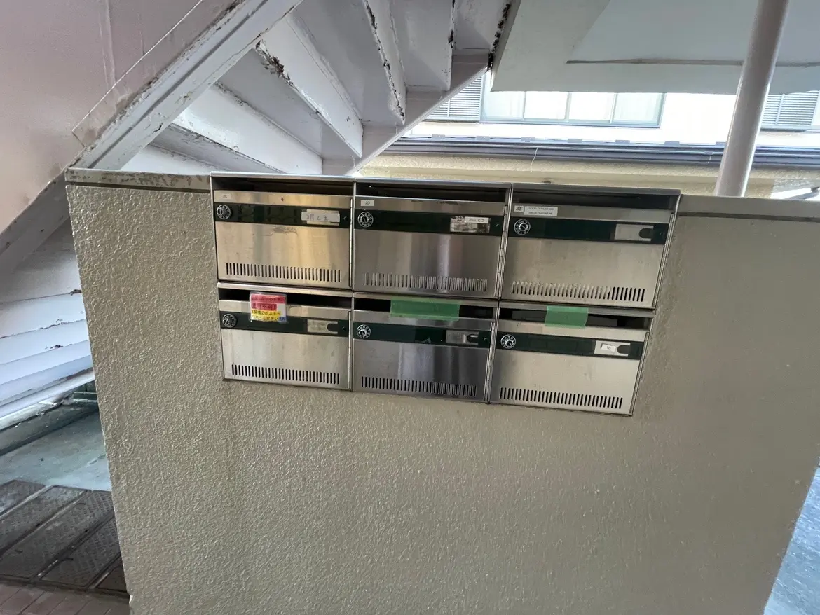 マンションの共用エントランスに設置された郵便受け、ステンレス製で番号表示あり
